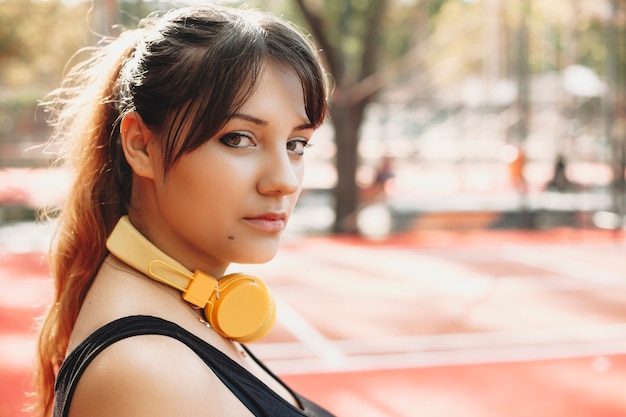 Foto chiuda sul ritratto di una giovane donna adorabile che esamina seriamente la macchina fotografica mentre fa la routine sportiva mattutina