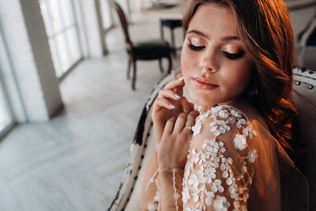 Close-up portrait of a luxurious bride in a wedding dress in the morning in her interior.