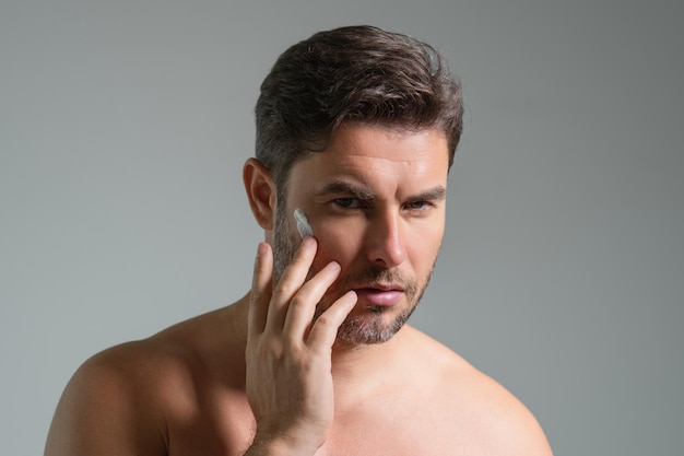 Photo close up portrait of man s applying cream on face handsome serious man enjoy fresh perfect skin appl