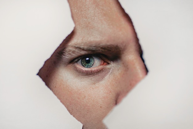 Close-up portrait of man seen through hole in paper