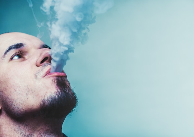 Photo close up portrait of a man vaping.