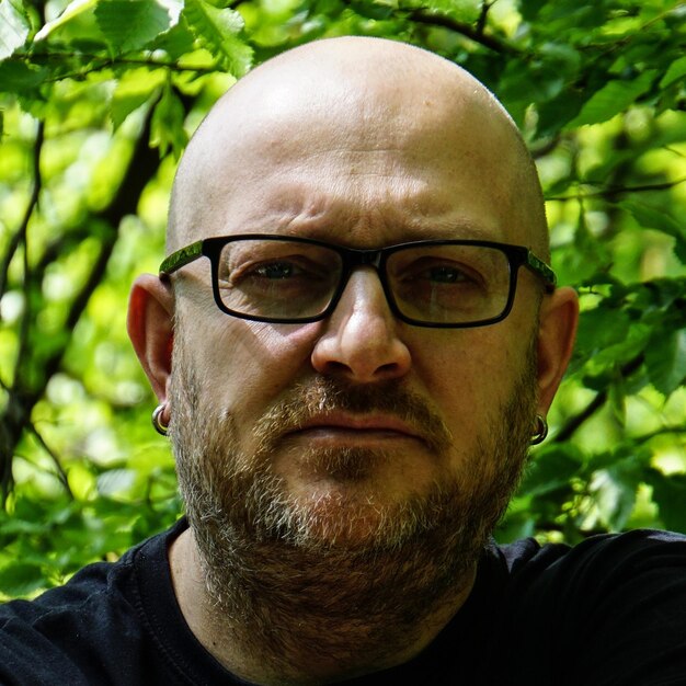 Close-up portrait of man wearing eyeglasses against plants