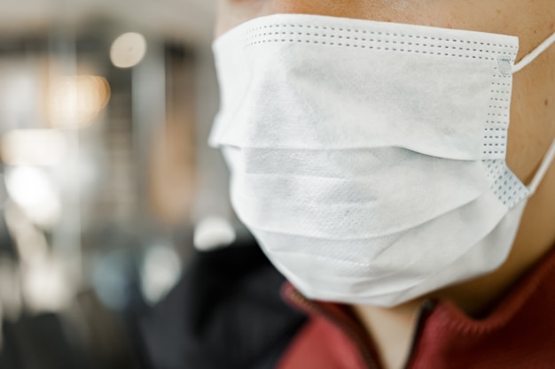 Close-up portrait of man wearing surgical mask to prevent from virus