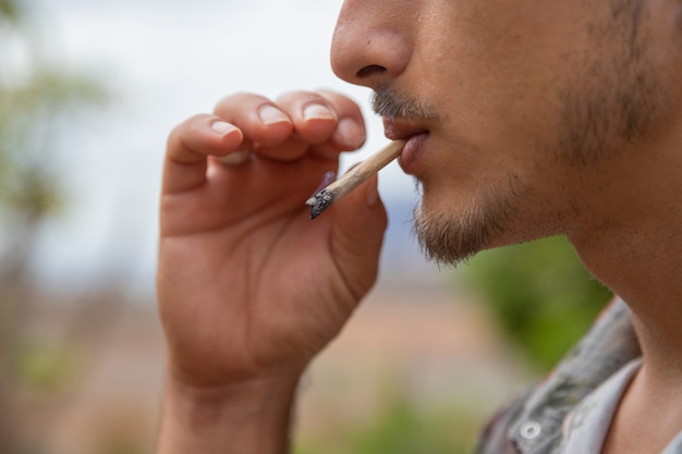 Close up portrait of a man who smokes a joint of marijuana