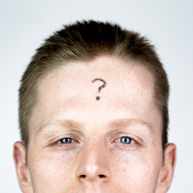 Close-up portrait of man with question mark on forehead against white background