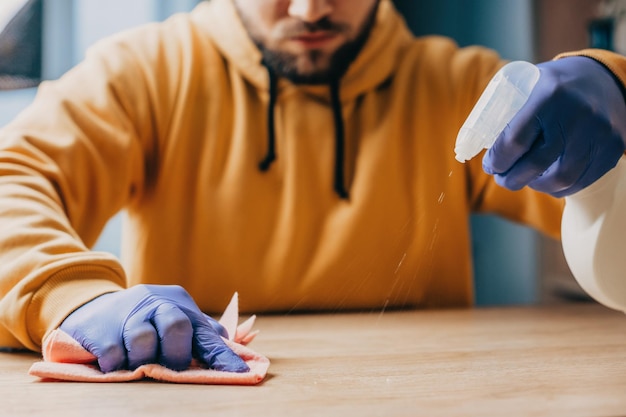 Photo close up portrait of mans hands with rubber gloves wiping wooden table man doing some cleaning work ...