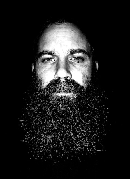 Photo close-up portrait of mature man with beard against black background