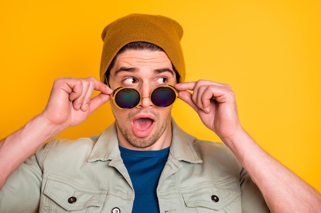 Photo close-up portrait of  nice attractive cool amazed emotional guy touching specs news reaction opened mouth isolated over bright vivid shine vibrant yellow color background