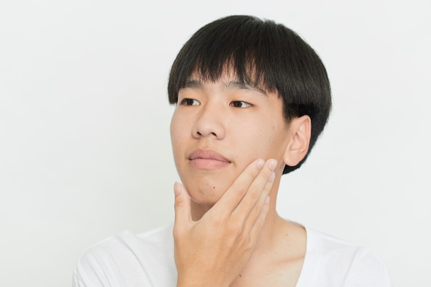 写真 白い壁にハンサムなかわいい若いアジア人男性の肖像画をクローズアップ