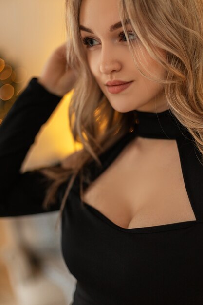 Фото Макро портрет молодой красивой элегантной женщины с прической в черной стильной одежде на фоне золотых огней боке. модель девушка на вечеринке
