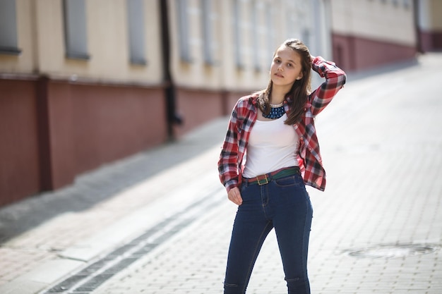Фото Крупный план портрета красивой девушки-подростка в яркой клетчатой рубашке на фоне городских улиц