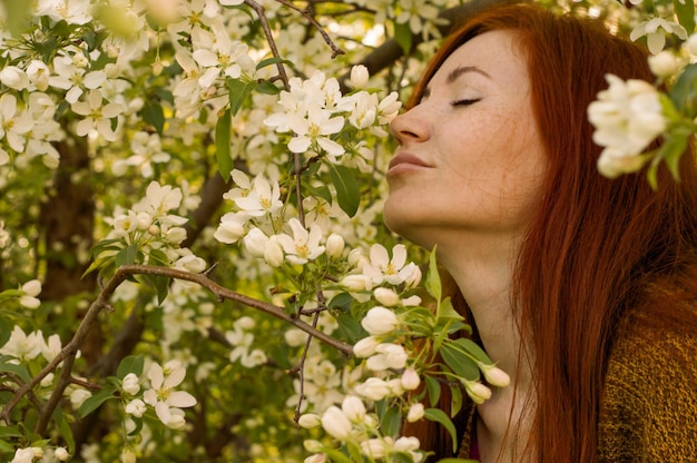 写真 白い花をかせた植物の背景にある美しい女性のクローズアップ肖像画