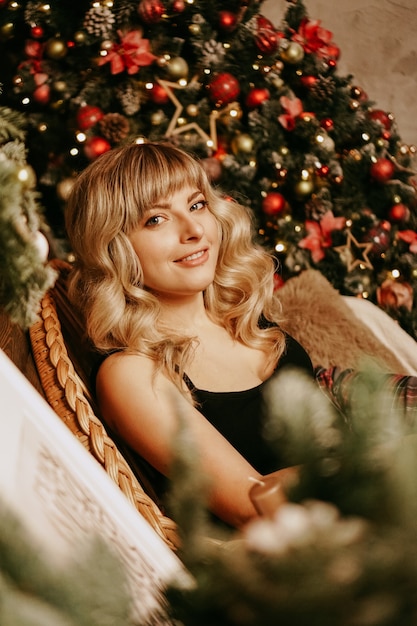 写真 ライトとクリスマスの背景に長い巻き毛の美しい少女の肖像画を閉じます。魔法の暖かい新年の写真。居心地の良いインテリア。