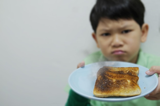 写真 皿に食べ物を入れた少年をクローズアップで描いた肖像画