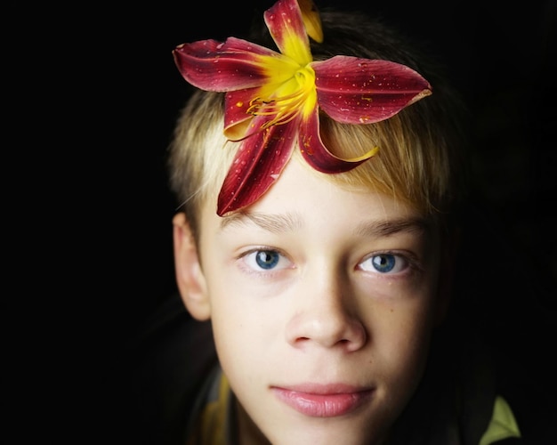 사진 검은 바탕 에 릴리 꽃 을 가진 소년 의 클로즈업 초상화