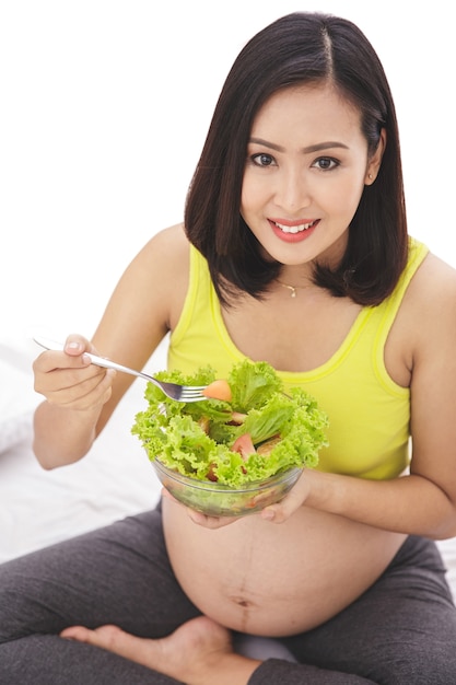 健康的な新鮮なサラダを食べる妊婦の肖像画をクローズアップ