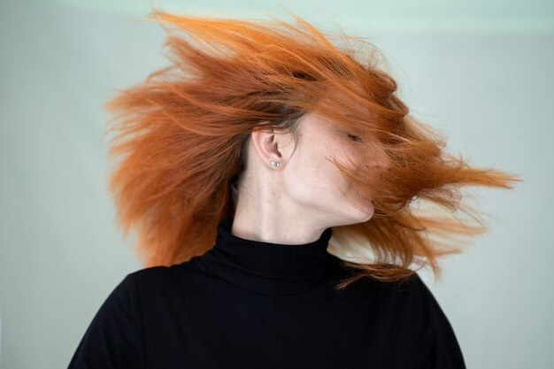 사진 바람에 날리는 긴 물결 모양 머리를 가진 예쁜 빨강 머리 여자의 초상화를 닫습니다.