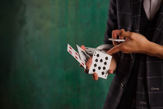 도박 카드와 젊은 남자의 클로즈업 초상화입니다. 잘 생긴 남자는 카드로 트릭을 보여줍니다. 마술사의 영리한 손