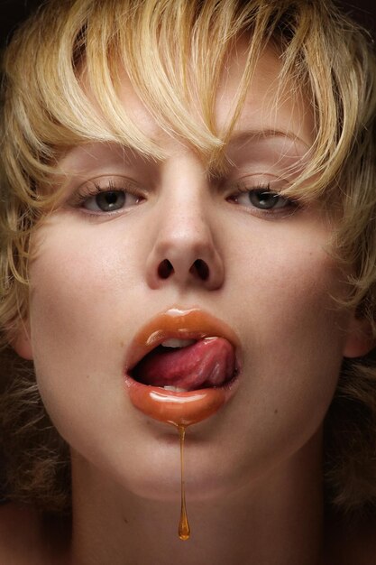 写真 唇から蜂蜜が滴る若い女性のクローズアップ肖像画