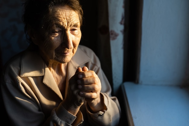 Close up portrait of an old woman praying