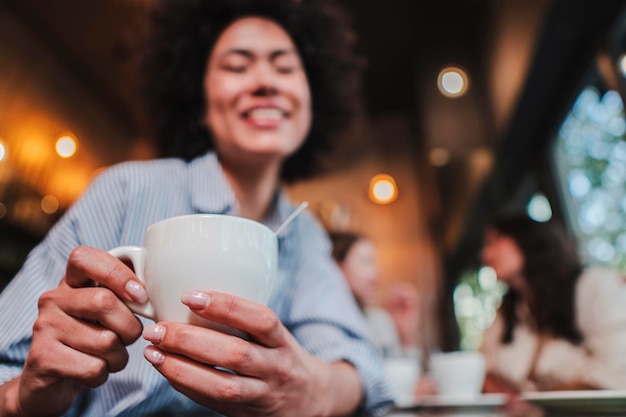 レストランでコーヒー カップを飲むを保持している一人の若い幸せな女性の肖像画を間近します。