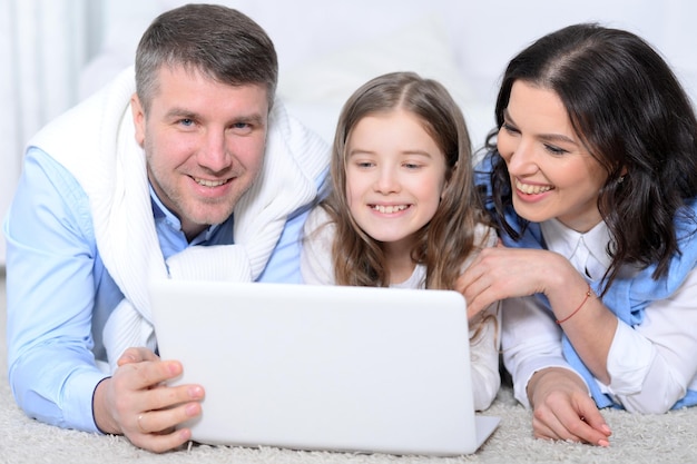 Close up portrait of parents and daughter using laptop in room