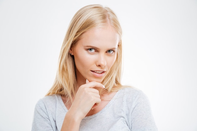 Close-up portrait of a pensive thougtful pretty blonde girl thinking about something isolated on the blue wall