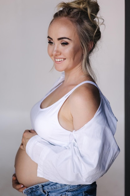 Close up portrait of pregnant woman in studio on white background beautiful future mother put her