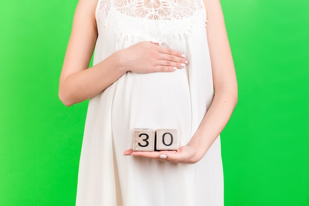 Close up portrait of pregnant woman in white dress showing cubes