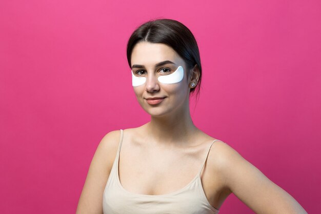 Close up portrait of pretty attractive girl with naked shoulders using patches under eyes