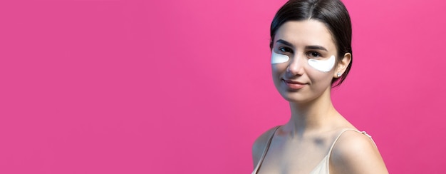 Close up portrait of pretty attractive girl with naked shoulders using patches under eyes