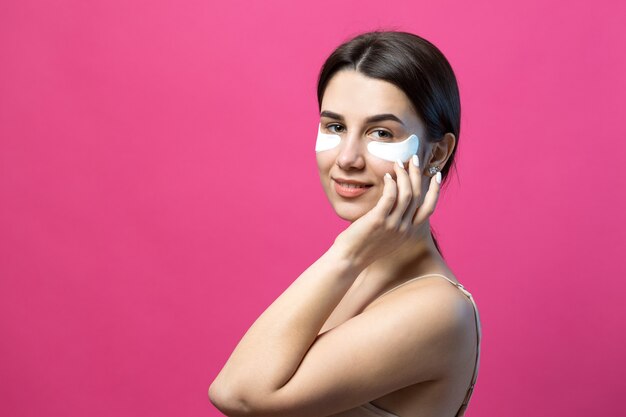 Close up portrait of pretty attractive girl with naked shoulders using patches under eyes