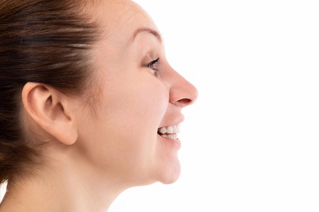 close-up portrait in profile of a young woman with teeth smiling.