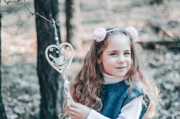 Close up portrait of red haired smiling girl in a headband playing in the forest