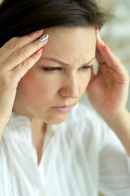 Close up portrait of sad ill young woman at home with headache