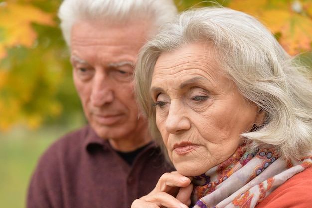 Close up portrait of sad senior couple in autumn park