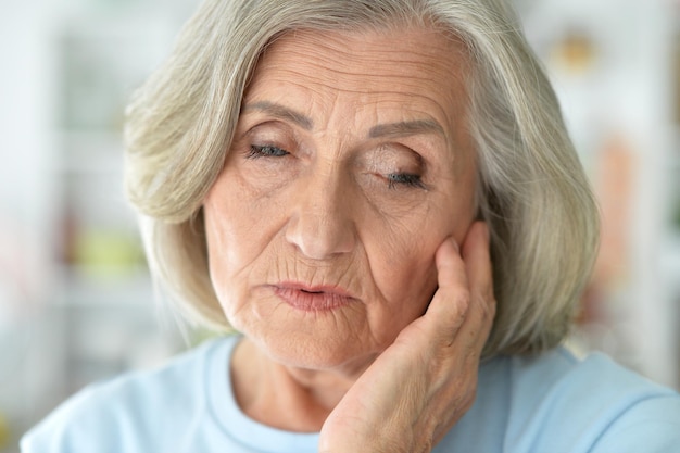 Close up portrait of sad senior woman posing at home