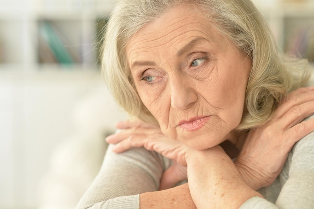 テーブルに座っている悲しい年配の女性の肖像画をクローズアップ