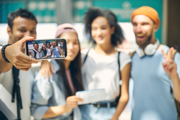 Photo close up portrait of screen mobile phone while man taking selfie on it in the international terminal