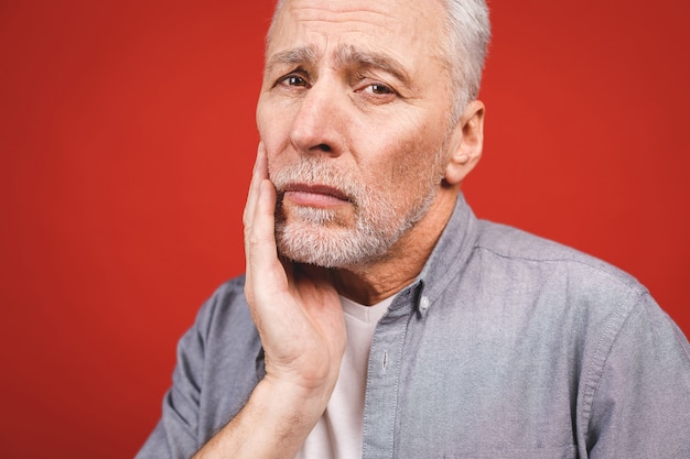 Close-up portrait of senior aged man suffering from toothache