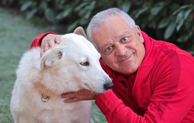 Foto ritratto in primo piano di un uomo anziano che accarezza un cane al parco