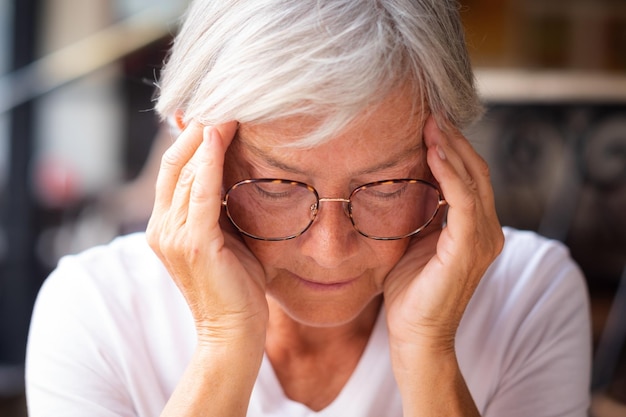 Close up portrait of senior woman closed eyes touching his head and temples for headache or problems to solve Bad migraine and health problems