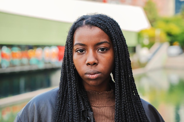 Close up portrait of serious african american woman with braids looking pensive at camera Front view of young girl Slow motion