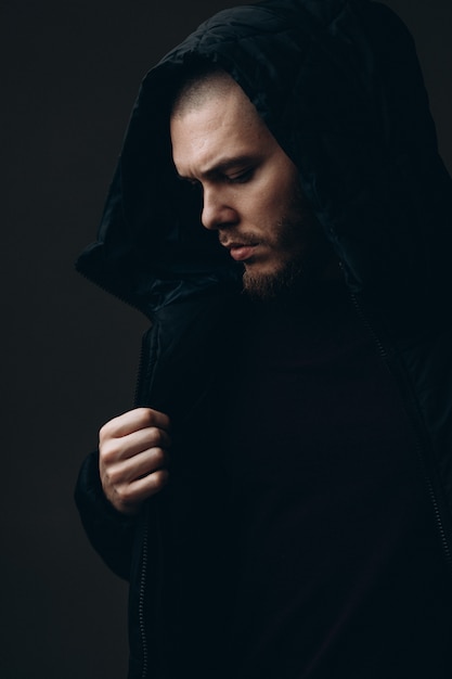 Close-up portrait of a serious young man in a jacket looking to the side on a gray space. bald with a beard