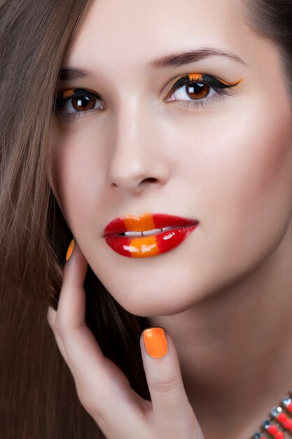 Close-up portrait of sexy caucasian young woman with golden glamour make-up and red bright manicure