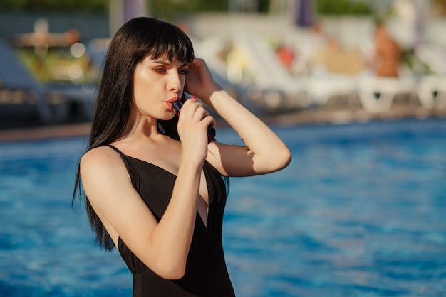 Close-up Portrait of sexy young (vaping) woman in pool. Vapor concept. Vaping e-Cigarette.