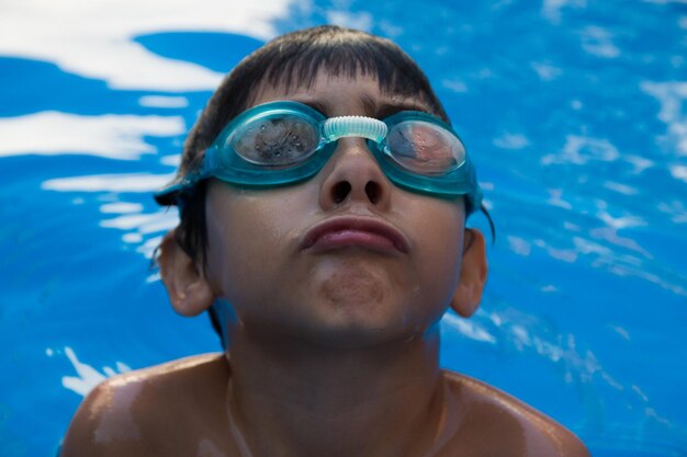 Foto ritratto in primo piano di un ragazzo senza camicia che nuota in piscina