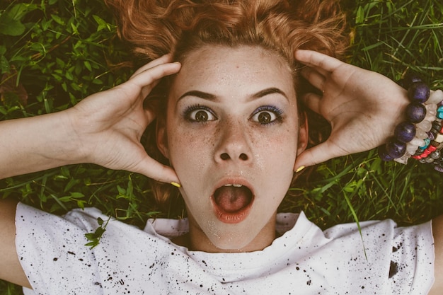 Photo close-up portrait of shocked woman lying on field