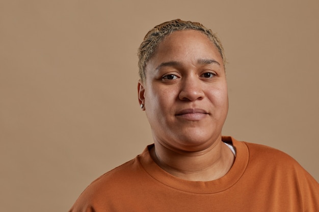 Close up portrait of short haired mixed race woman looking at camera while posing against neutral background in studio, copy space