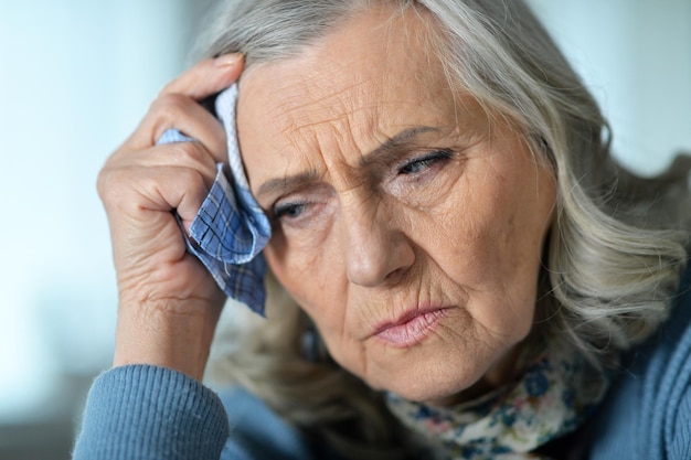 Close up portrait of sick senior woman with handkerchief